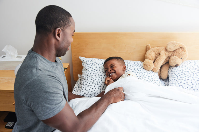 Man tucking child into bed