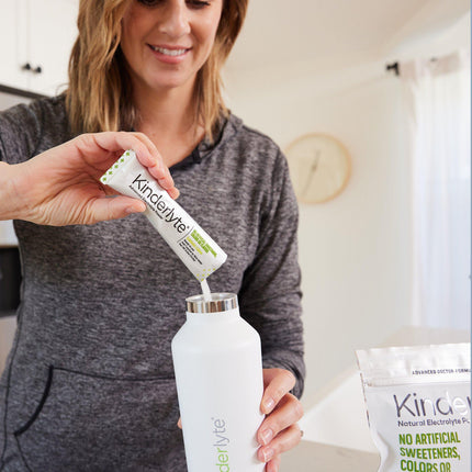 Person pouring a KinderLyte packet into a water bottle.