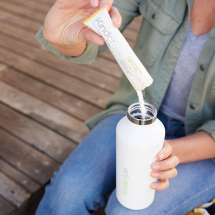 Person pouring a KinderLyte packet into a water bottle.