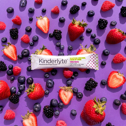 Image of a KinderLyte Powder packet on top of fresh, mixed berries.